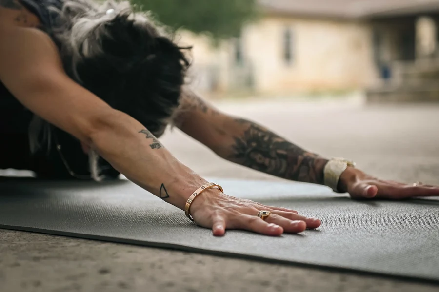 Posture de l'enfant en yoga, bras tendus au sol devant soi, sur un tapis